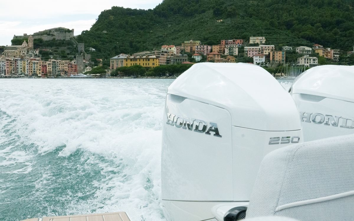 Deux moteurs hors-bord Honda BF250 vus de la poupe, un bateau en navigation le long de la côte