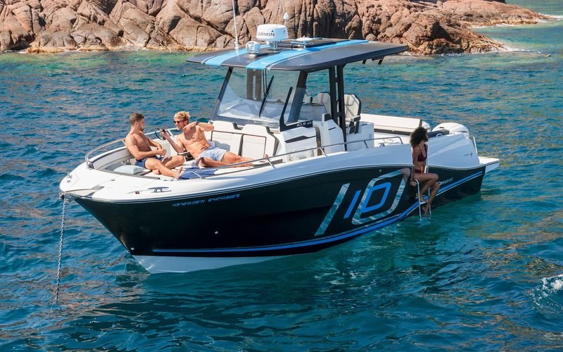 Bateau à moteur Jeanneau au mouillage dans une crique, plusieurs personnes à bord